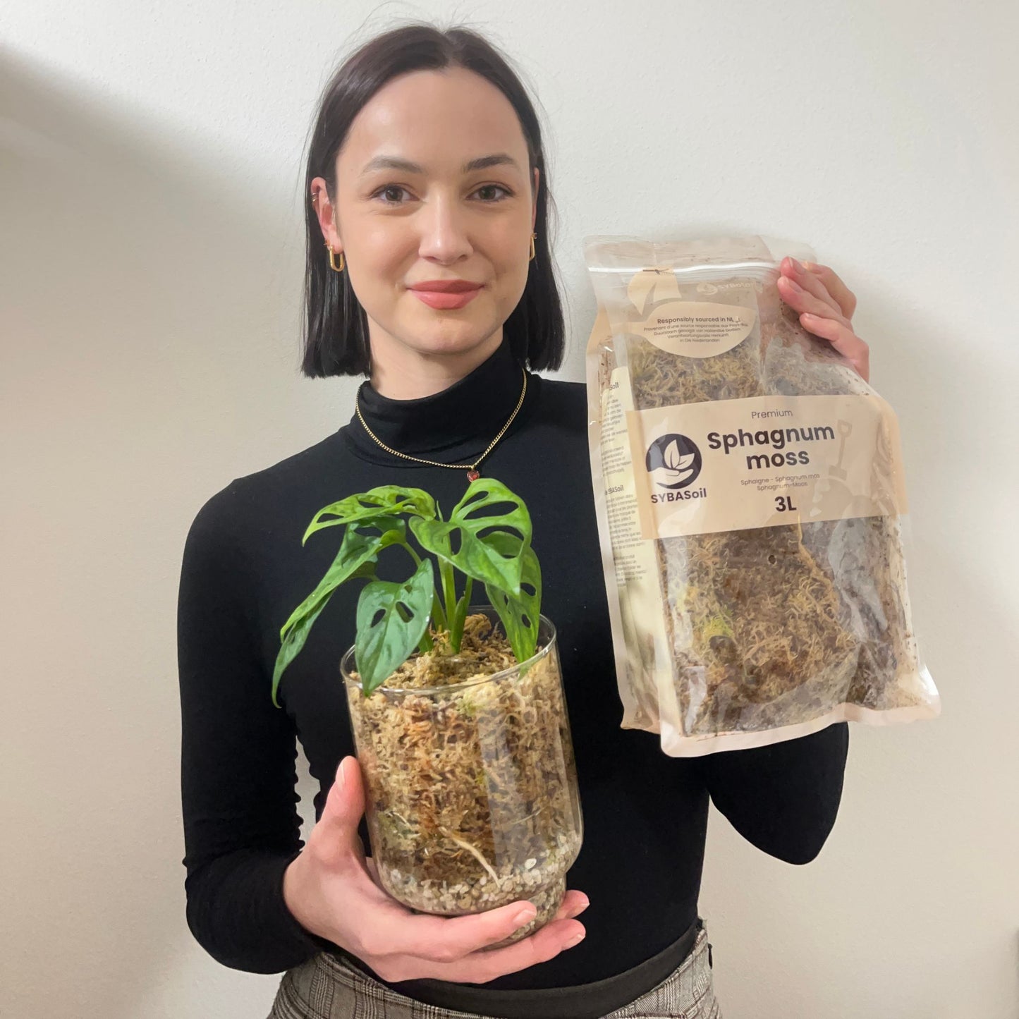 Kvinde holder potteplante monstera og en pose sphagnum-mos